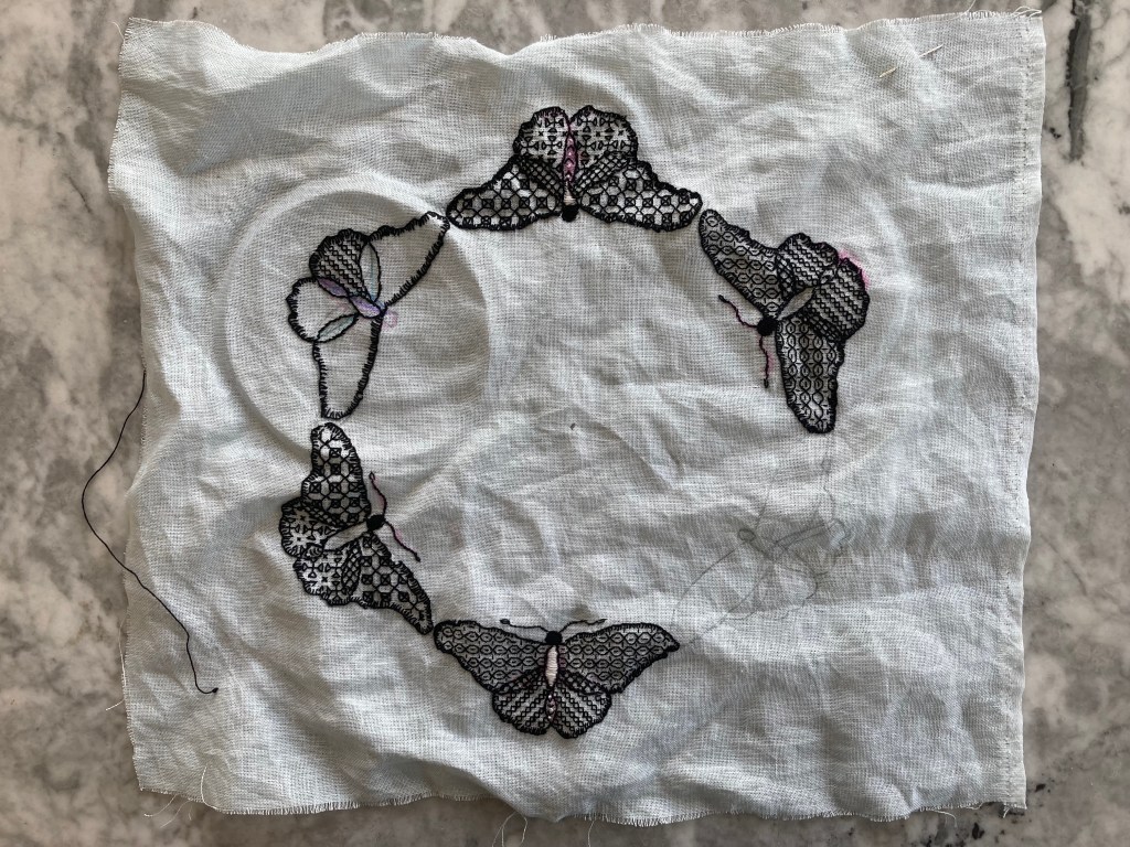 Unfinished embroidery project, blackwork butterflies on pale blue fabric
