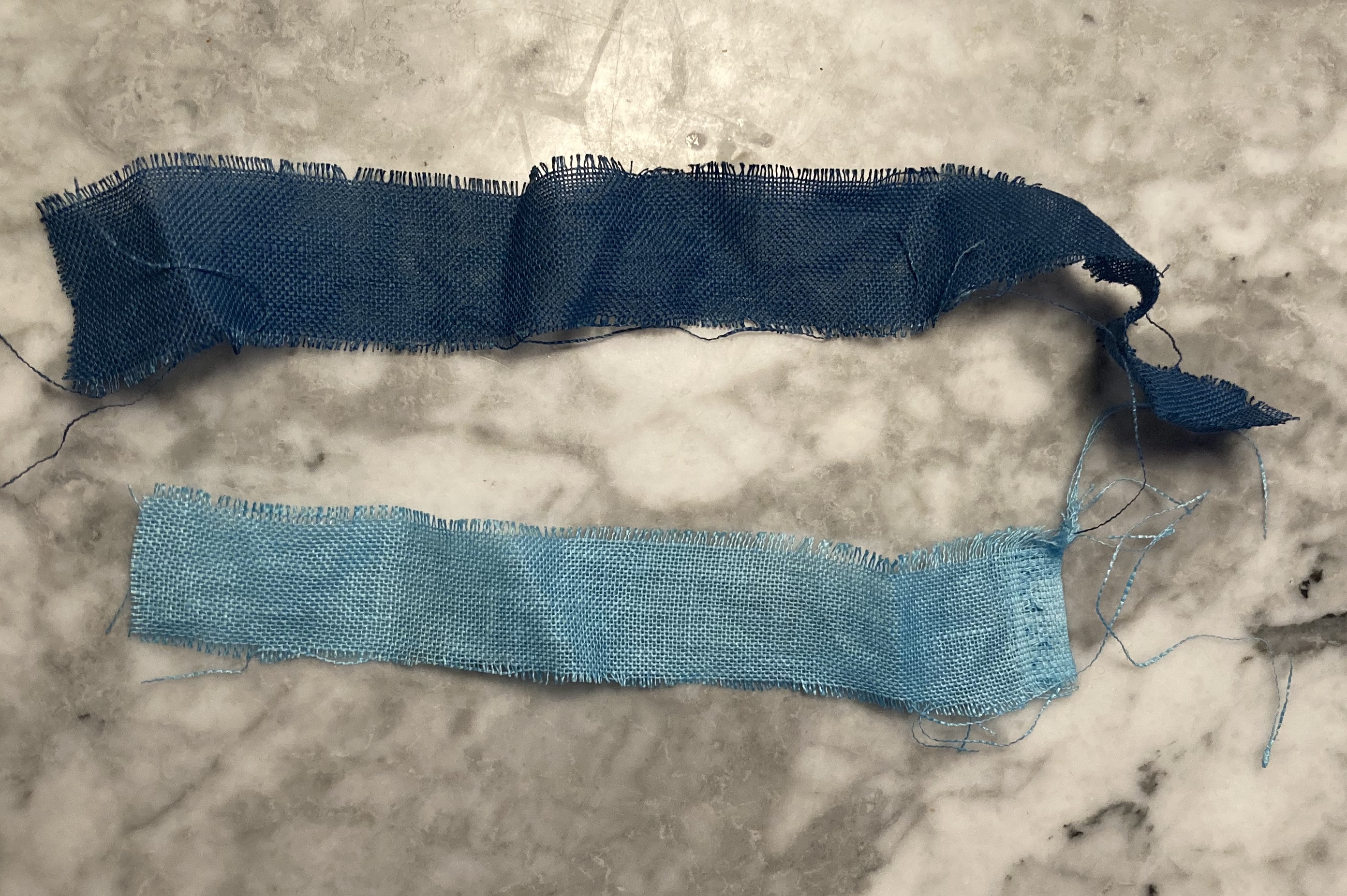 Two strips of dyed fabric in different shades of blue