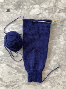 Incompletely knitted sleeve of a cardigan in blue wool